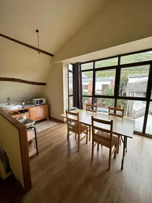 a living room with a table and chairs and a kitchen at Albergue de peregrinos Compostela in Molinaseca