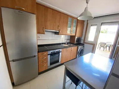 a kitchen with a stainless steel refrigerator and a table at Apartamento a 5 min caminando de la Playa Sta. Cristina, Oleiros (Terraza, Parkin, ) in Oleiros
