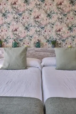 two beds in a room with a floral wallpaper at Pensión A Solaina 2 in O Pino