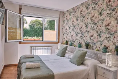 a bedroom with two beds and floral wallpaper at Pensión A Solaina 2 in O Pino