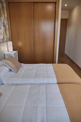 a bedroom with a large white bed with a wooden wall at Pensión A Solaina 3 in O Pedrouzo