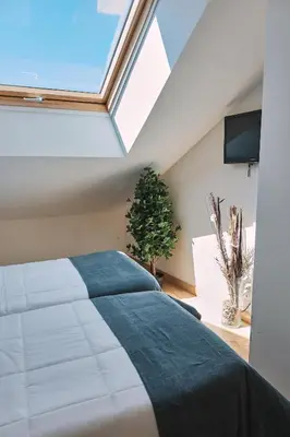 a bedroom with a large bed and a skylight at Pensión A Solaina 3 in O Pedrouzo