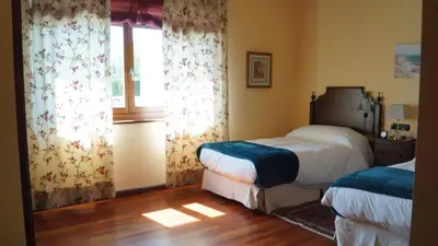a bedroom with two beds and a window at Hotel Batán in Villalba