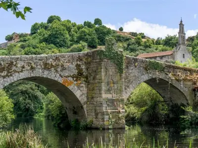 an old stone bridge over a river with a church at Apartment in Ourense near Hot Springs in Ourense