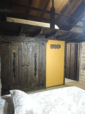 a bed with a wooden headboard with a yellow wall at CASERIO RECTORAL DESTERIZ in Ourense