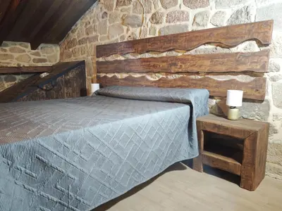 a bedroom with a bed and a stone wall at CASERIO RECTORAL DESTERIZ in Ourense