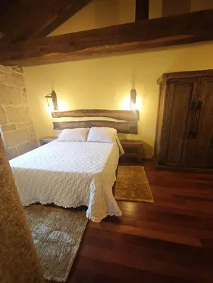 a bedroom with a white bed and wooden floors at CASERIO RECTORAL DESTERIZ in Ourense