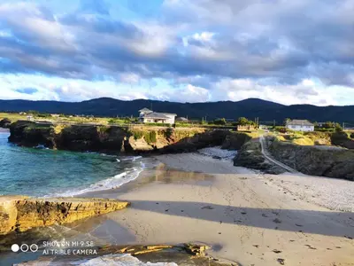 a view of a beach with a house in the background at Villa sobre el mar con acceso a la playa , ideal para familias y grupos in Ribadeo