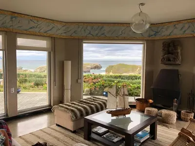 a living room with a couch and a large window at Villa sobre el mar con acceso a la playa , ideal para familias y grupos in Ribadeo