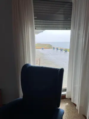 a chair in front of a window with a view of the ocean at Villa sobre el mar con acceso a la playa , ideal para familias y grupos in Ribadeo