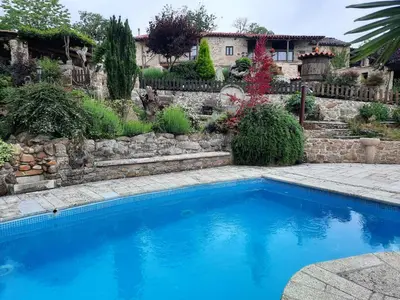 a blue swimming pool in a yard with a stone wall at Apartamentos Alburiñas Ribeira Sacra in Bolmente