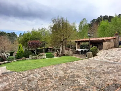 a garden with a stone pavilion and a picnic table at Apartamentos Alburiñas Ribeira Sacra in Bolmente