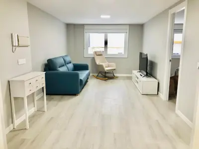 a living room with a blue couch and a television at Apartamento Muralla in Lugo