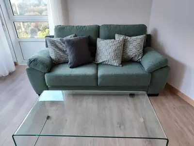 a green couch in a living room with a glass table at Apartamento Calzada Romana in Lugo