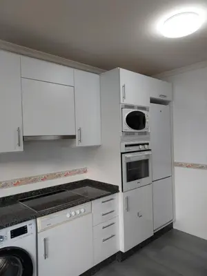 a white kitchen with white cabinets and appliances at Apartamento Calzada Romana in Lugo