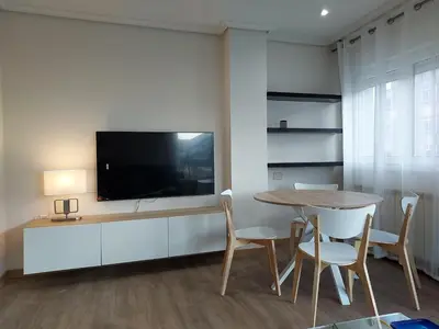 a dining room with a table and a flat screen tv at Apartamento Calzada Romana in Lugo