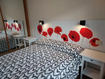 a bedroom with a bed with red poppies on the wall at Apartamento Calzada Romana in Lugo