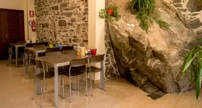 a restaurant with tables and chairs and a stone wall at Albergue de la Piedra in Villafranca del Bierzo