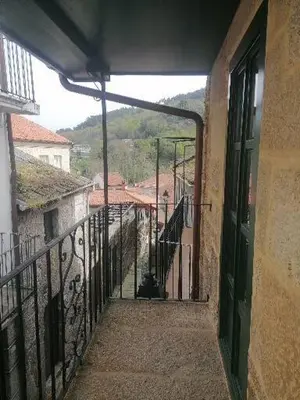 an alleyway with a balcony with a cat sitting on it at Casiña da Madalena in Ribadavia
