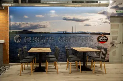 a restaurant with tables and chairs in front of a mural at Hostal Restaurante Cuatro Caminos in Cubillos del Sil