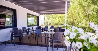 a restaurant with tables and chairs on a deck at Hostal Restaurante Cuatro Caminos in Cubillos del Sil