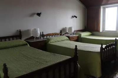a bedroom with four beds with green sheets and a window at Albergue Turístico Silleda in Silleda