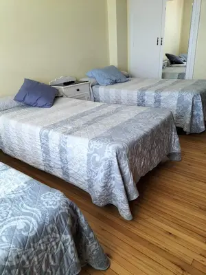 three beds in a room with wood floors at Albergue Turístico Silleda in Silleda