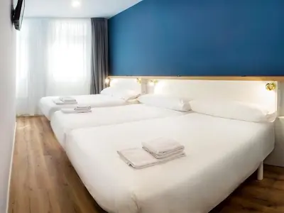 two beds in a hotel room with a blue wall at Casa do cabo in Arzúa