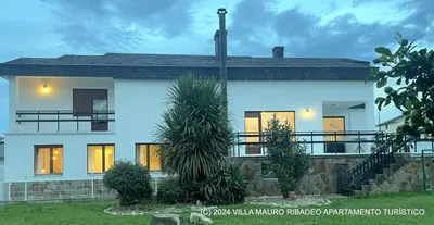 a white house with its lights on at Villa Mauro Ribadeo Apartamento Turístico in Ribadeo