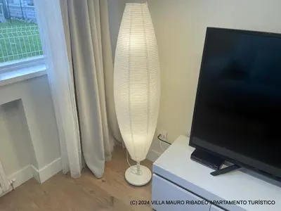 a white lamp is sitting next to a television at Villa Mauro Ribadeo Apartamento Turístico in Ribadeo