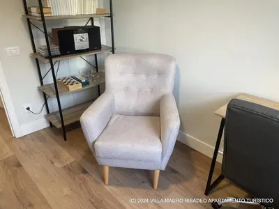 a chair sitting in a room next to a shelf at Villa Mauro Ribadeo Apartamento Turístico in Ribadeo