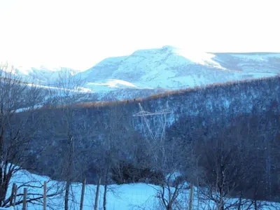 a snow covered hill with trees and a mountain at Casa de Lucas in Fonfría