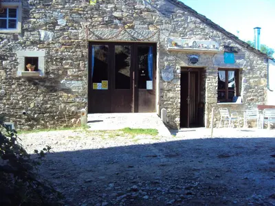 a stone building with a door and a dog in a window at Casa de Lucas in Fonfría