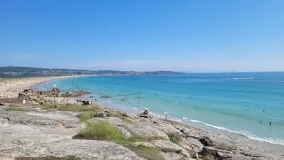 a beach with people in the water and people in the ocean at La casita 