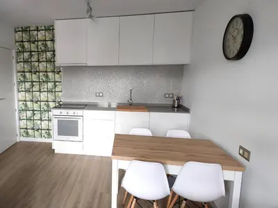 a kitchen with a table and white cabinets and a clock at Second Home Arzúa apartamentos in Arzúa