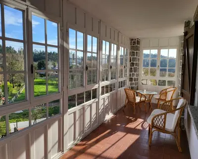 a room with windows and a table and chairs at Hostal Boavista in Costoia