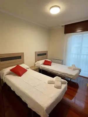 a room with two beds with red pillows at Alojamiento Apostol 2 in Melide