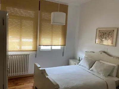 a bedroom with a bed with white sheets and windows at Casa Morín, apartamento Ribeira Sacra in Monforte de Lemos