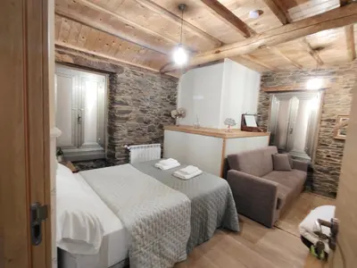 a bedroom with a bed and a chair in a room at A casa do lajueiro in Arzúa