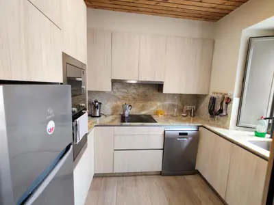 a kitchen with wooden cabinets and a stainless steel refrigerator at A casa do lajueiro in Arzúa