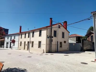 a white building with red chimneys on a street at A casa do lajueiro in Arzúa
