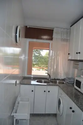 a small kitchen with a sink and a window at Precioso ático a pie de playa, en Miño. in Miño
