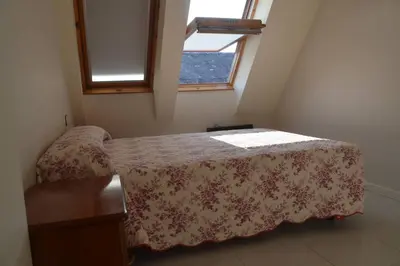a small bedroom with a bed with a flowered blanket at Precioso ático a pie de playa, en Miño. in Miño