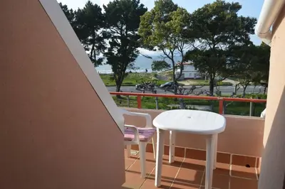 a balcony with a white table and two chairs at Precioso ático a pie de playa, en Miño. in Miño