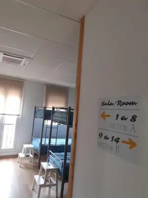 a room with bunk beds and a sign on the wall at ALBERGUE LEMAVO in Monforte de Lemos
