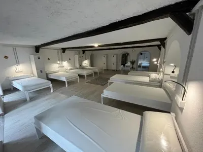 a room with white beds and chairs in it at HOSTEL PORTON in Lugo