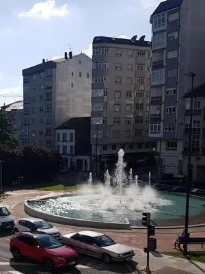 a fountain in a parking lot with cars parked around it at MAXIMO CONFORT in Lugo