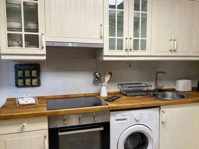 a kitchen with white cabinets and a sink and a dishwasher at Apartamentos Rurales Ca Lulón in Navelgas