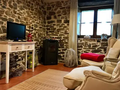 a living room with a tv and a stone wall at Apartamentos Rurales Ca Lulón in Navelgas