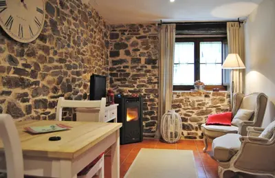 a living room with a stone wall with a clock on the wall at Apartamentos Rurales Ca Lulón in Navelgas